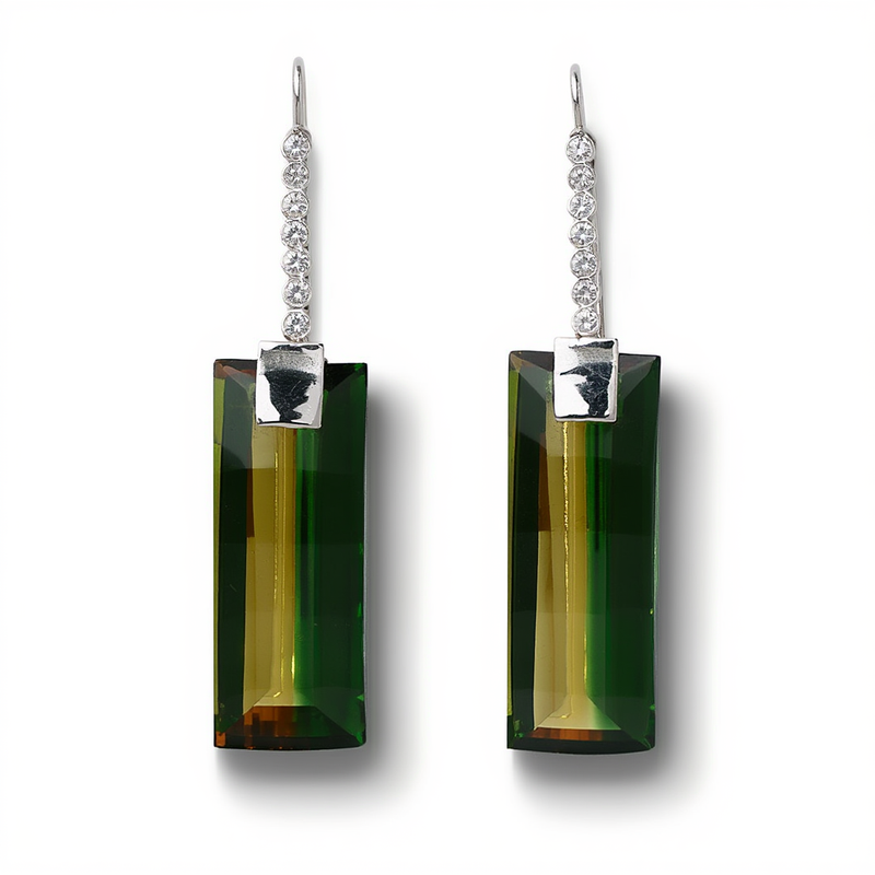 A pair of linear drop earrings featuring a vertical string of round diamonds holding a large rectangular emerald cut green tourmaline from a custom jewelry creator